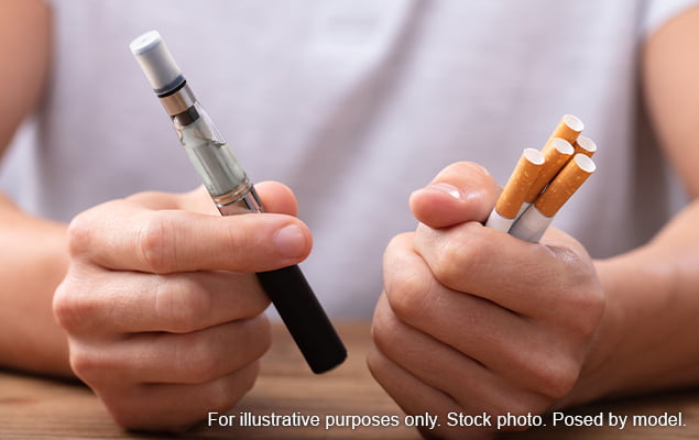 Man holding vape and cigarettes to compare them